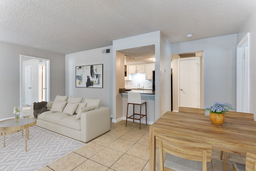 A living room with a couch, coffee table, and a dining table.