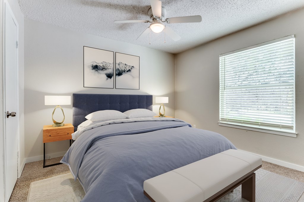 A bedroom with a bed, a bench, and two lamps.