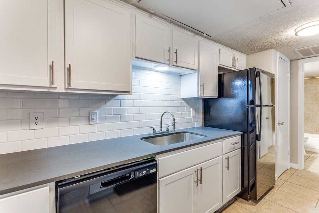 a kitchen with white cabinets and a sink and a refrigerator