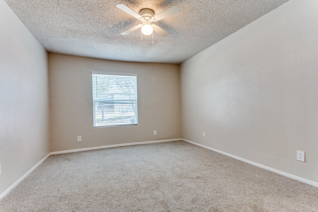an empty room with a ceiling fan and a window