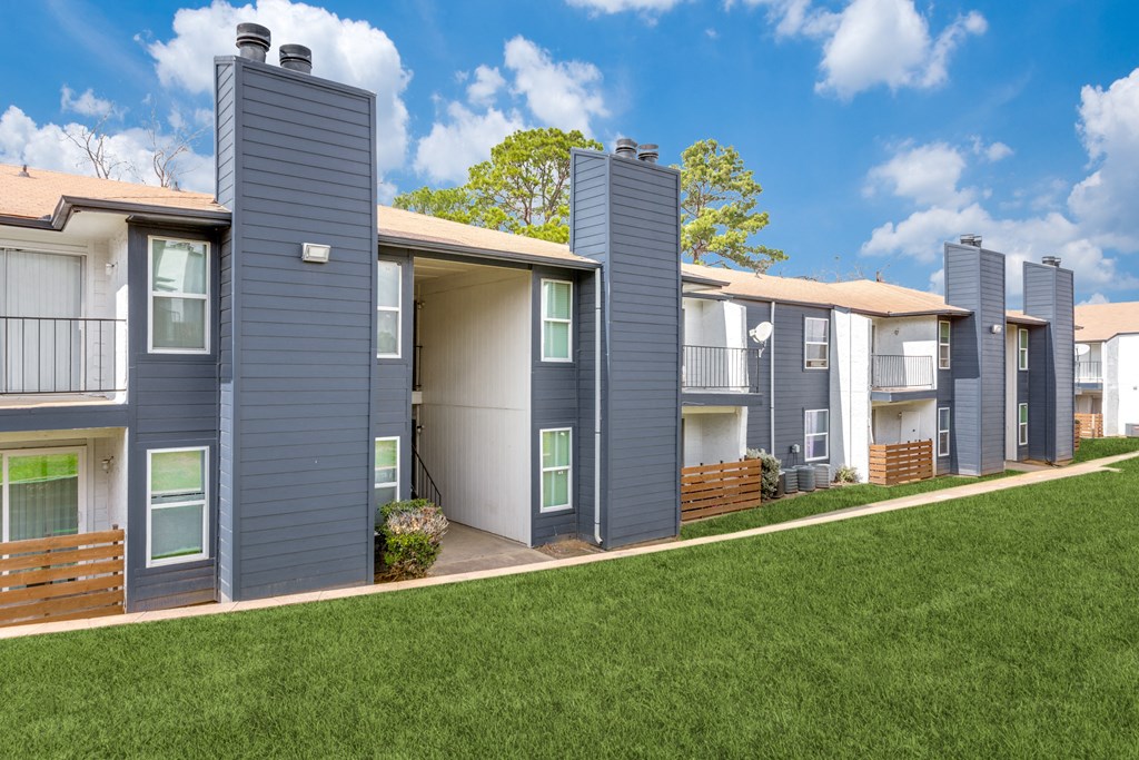 a row of townhomes with gray roofs and green grass