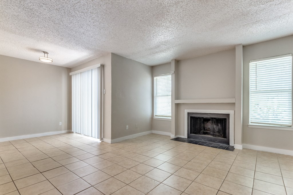an empty living room with a fireplace and tiled floors