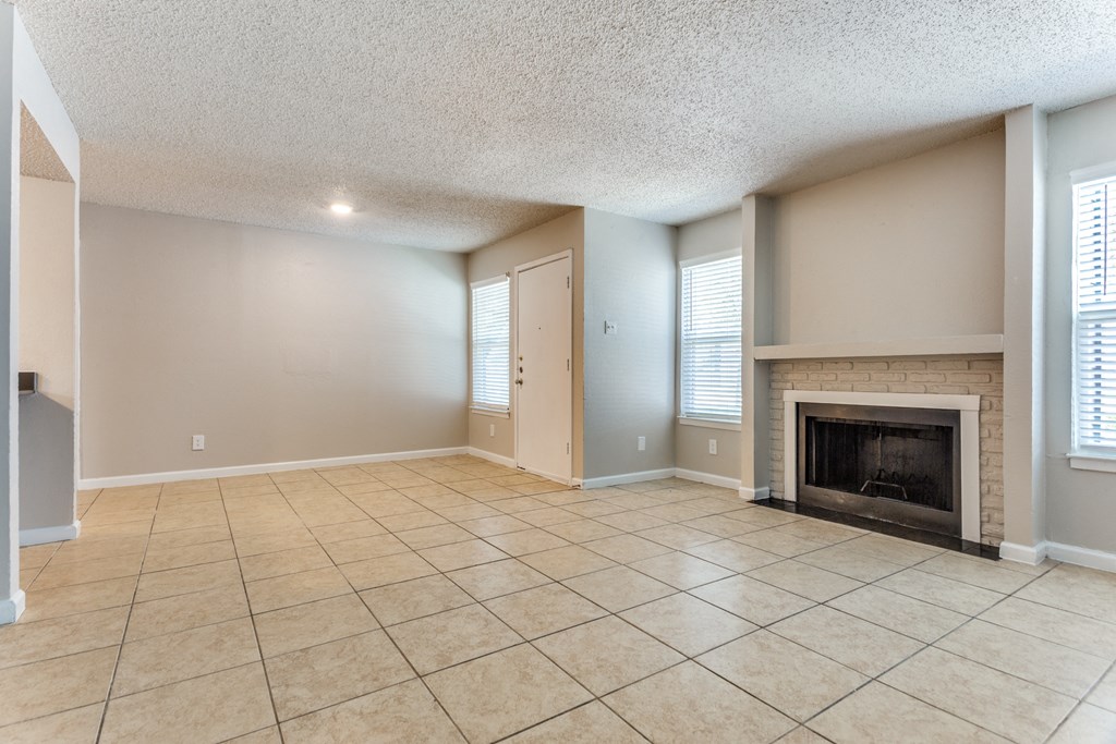 an empty living room with a fireplace and tile flooring