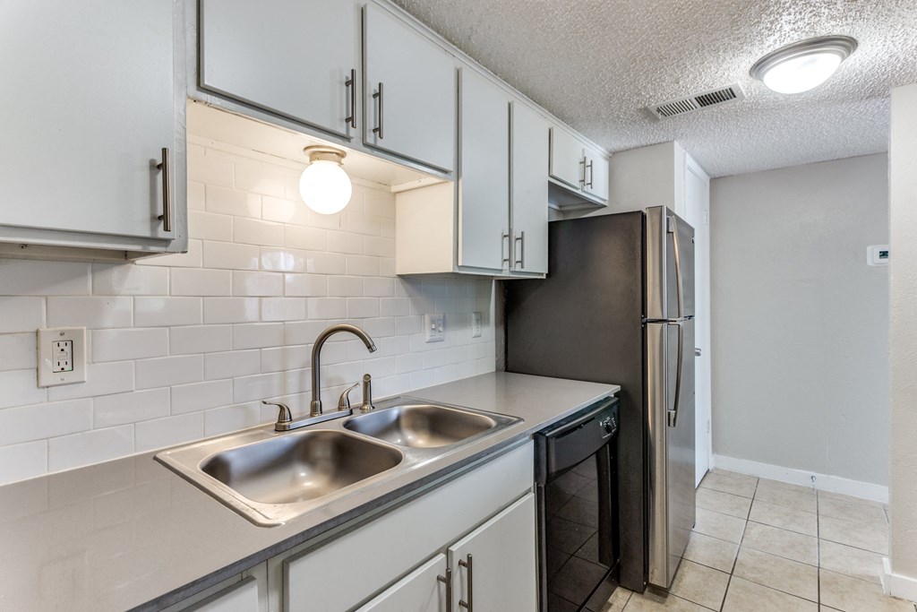 an empty kitchen with a sink and a refrigerator
