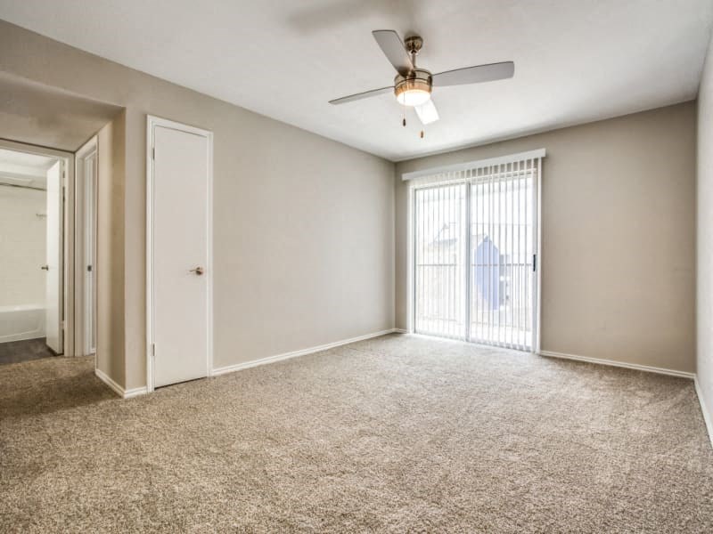 an empty living room with a ceiling fan and a window