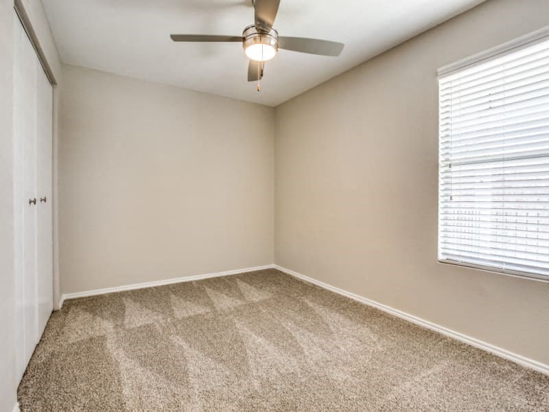 an empty room with a ceiling fan and a window
