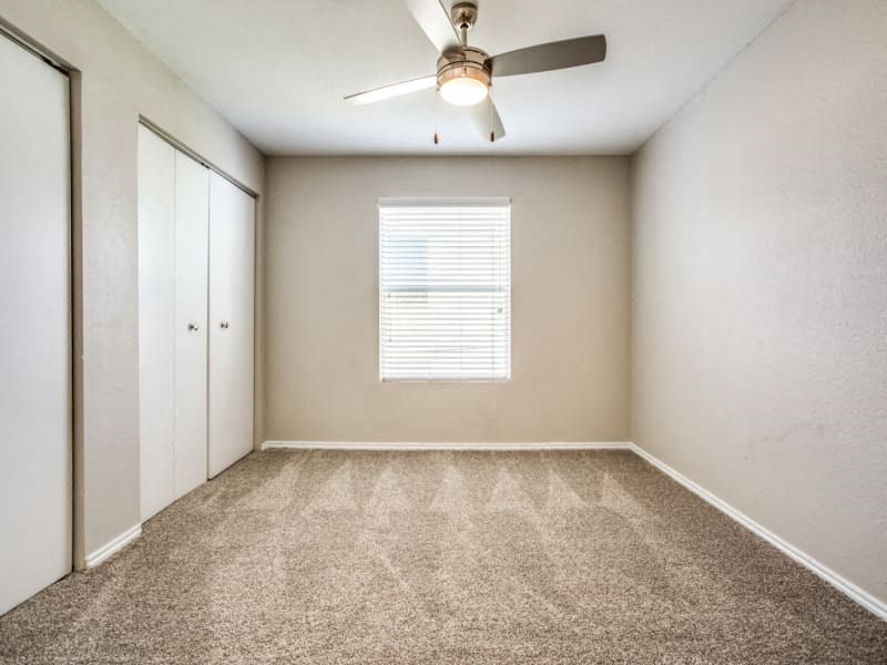 an empty room with a ceiling fan and a closet
