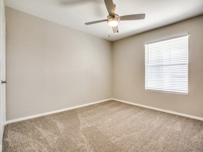 an empty room with a ceiling fan and a window