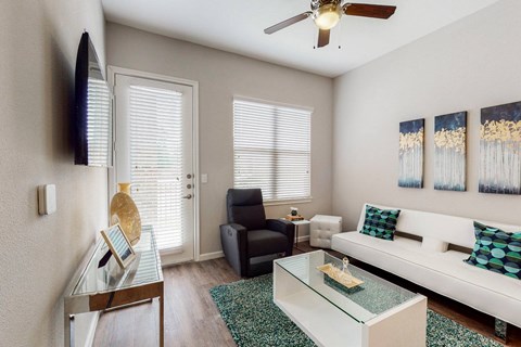 A living room with a glass coffee table and a white couch.