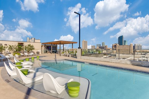 A pool area with white chairs and green cushions.