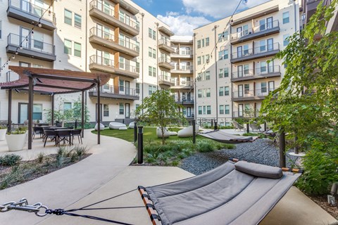 A playground with a slide in the middle of a courtyard surrounded by apartment buildings.