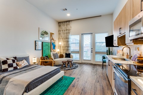 A bedroom with a large bed and a kitchen area in the same room.