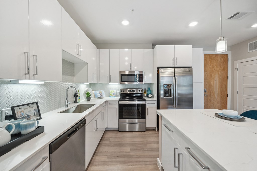 a large white kitchen with stainless steel appliances and white counters