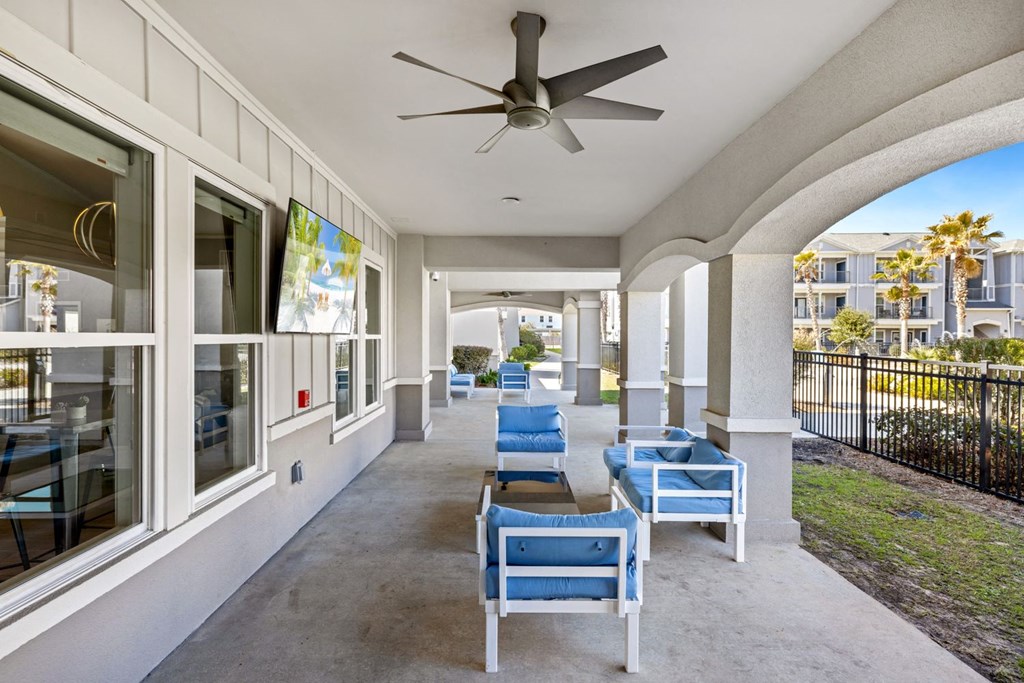 A patio with a ceiling fan and blue chairs.