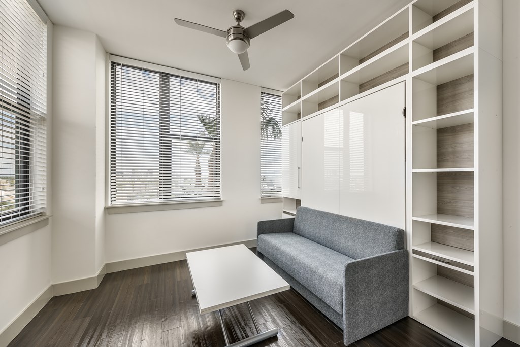A living room with a grey couch, a white coffee table, and a ceiling fan.