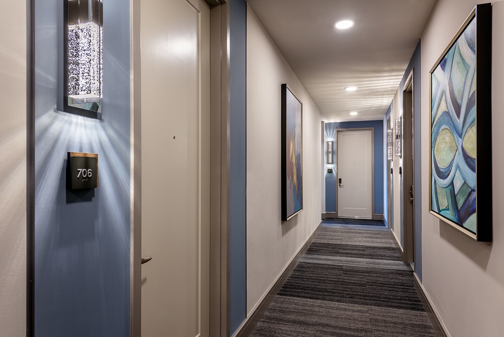 A hallway with a blue wall and a door with the number 706 on it.