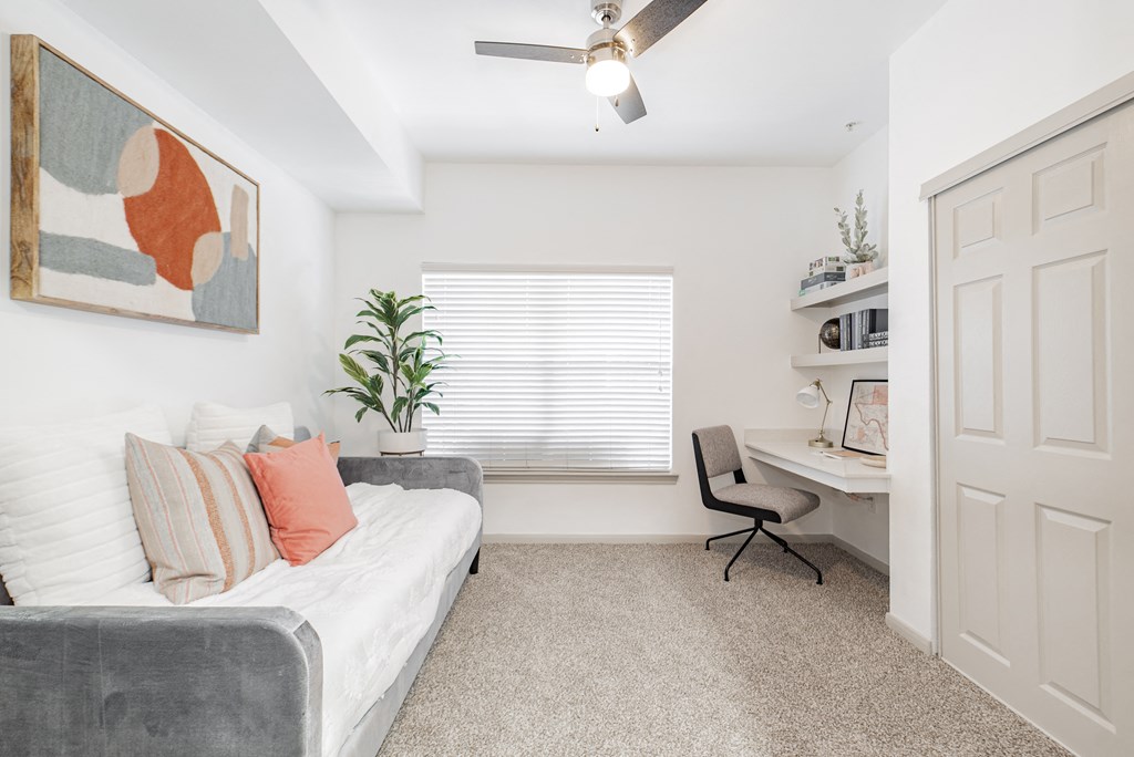 a bedroom with a couch and a desk and a window