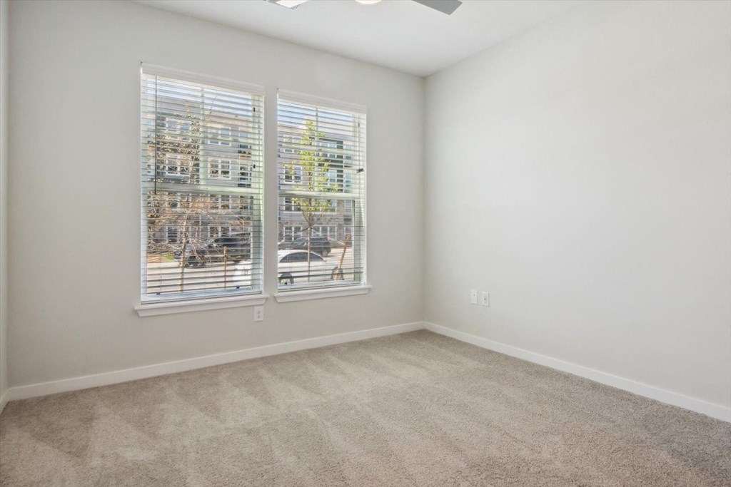 an empty living room with a window and carpet