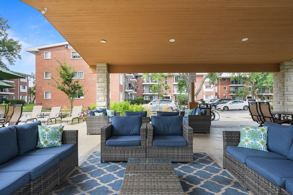 a patio with couches and chairs and a wooden ceiling