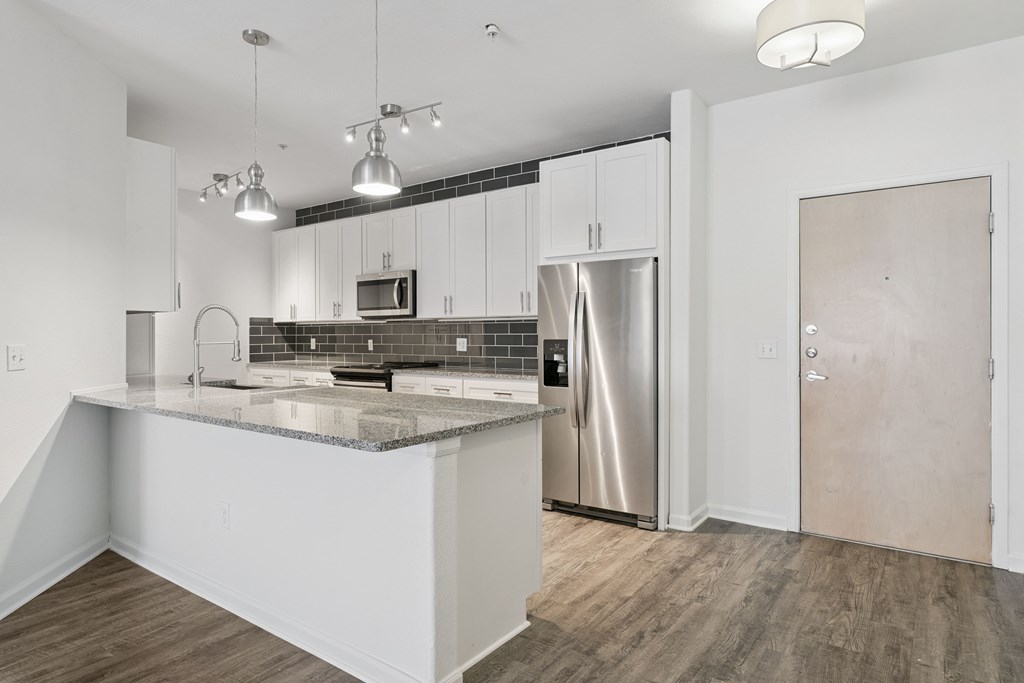 A kitchen with a refrigerator, microwave, and oven.