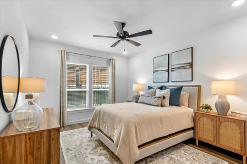 A bedroom with a large bed, a ceiling fan, and two lamps.