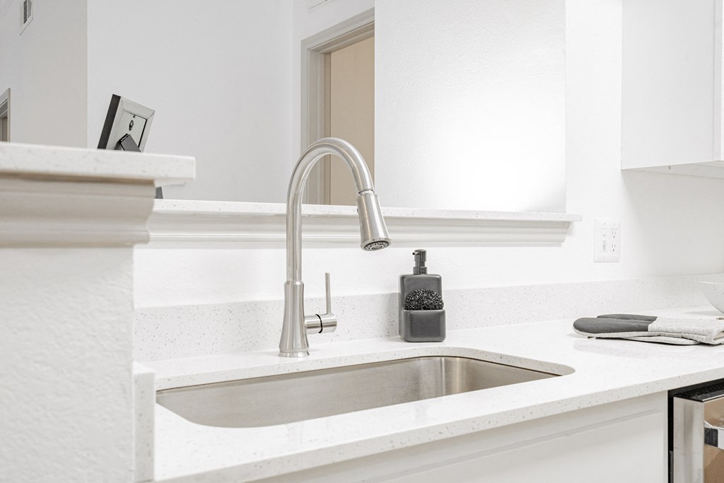 a white kitchen with a sink and a faucet