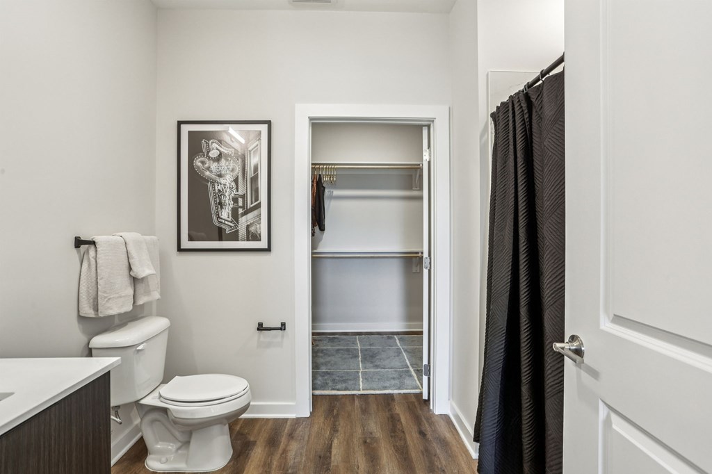 A bathroom with a toilet, a sink, and a picture on the wall.