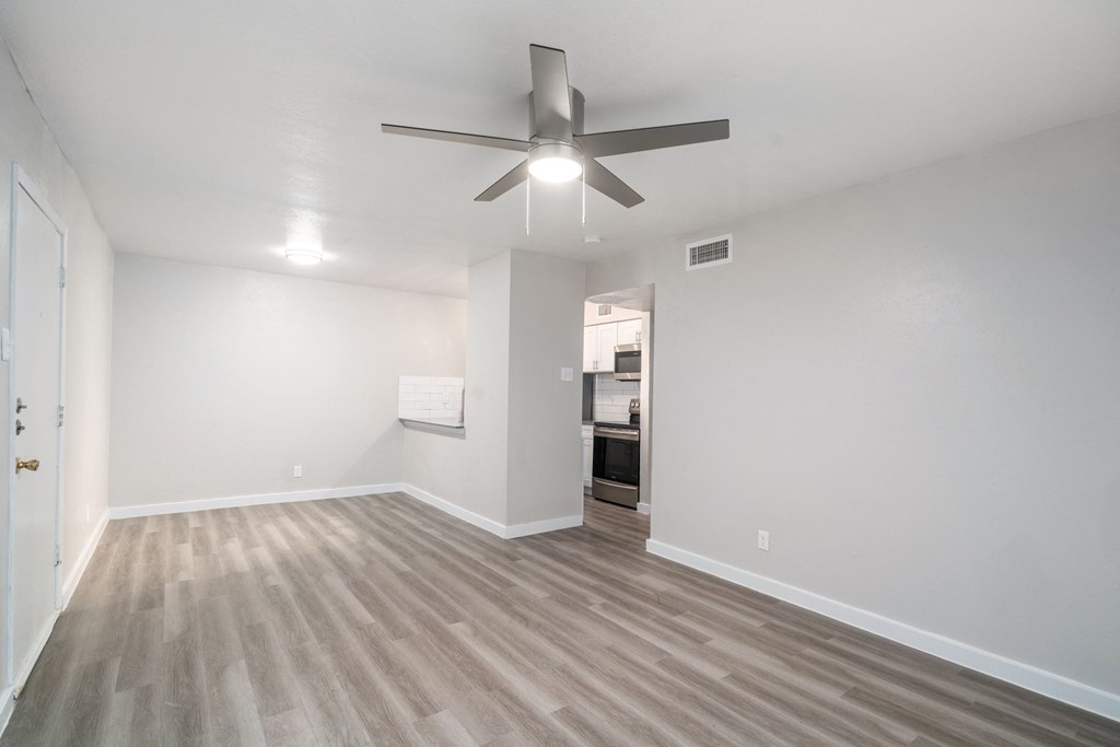 a spacious living room with a ceiling fan and hardwood floors