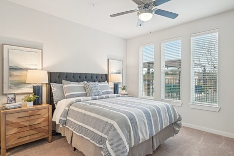 A bedroom with a large bed and a ceiling fan.