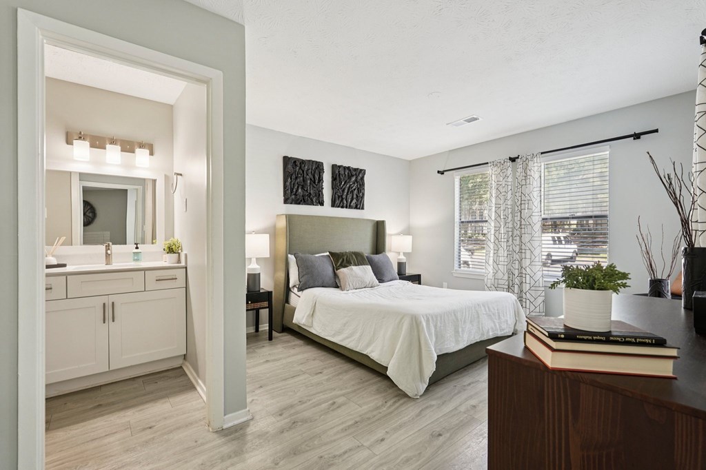 A bedroom with a bed, nightstand, and a window with blinds.