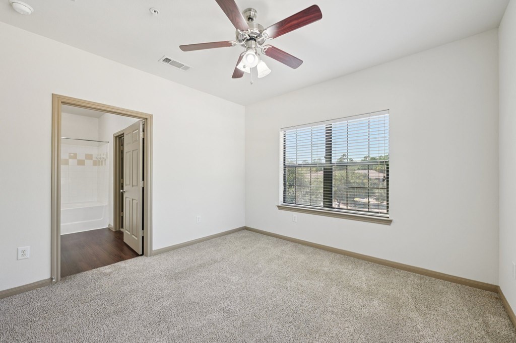 A room with a ceiling fan and a window with blinds.