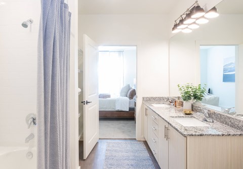 a bathroom with a shower and a sink and a bedroom with a bed