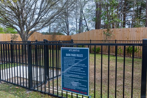 a sign in front of a fence with a pool behind it