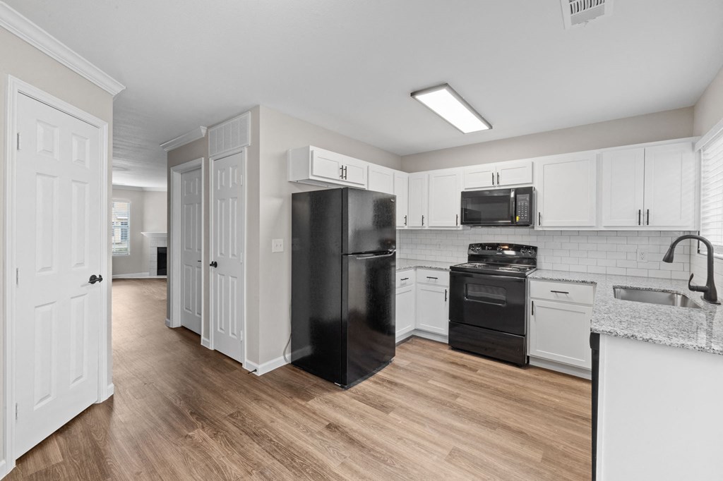 A kitchen with black appliances and white cabinets.