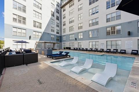 A large outdoor pool area with lounge chairs and a bar area.