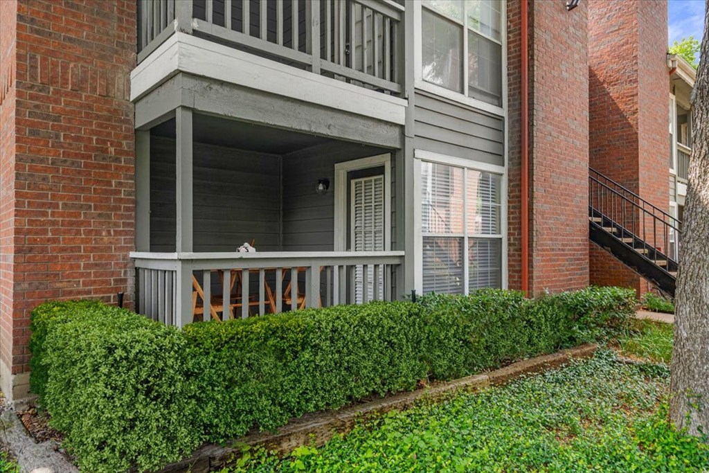 A balcony with a railing and a hedge in front of a brick building.