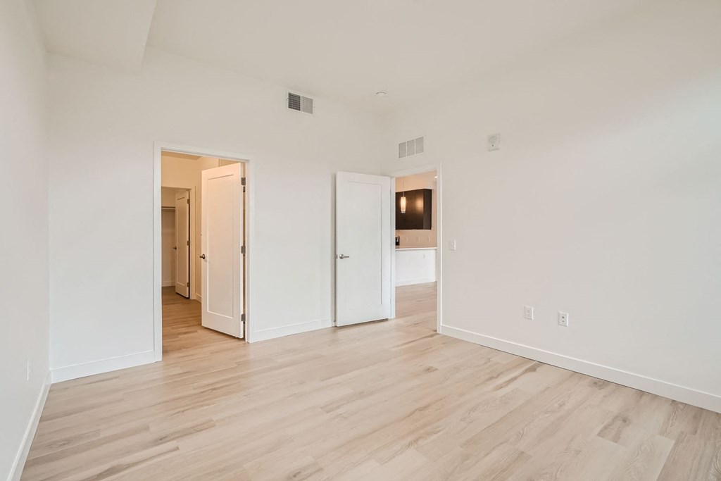 a bedroom with hardwood floors and white walls