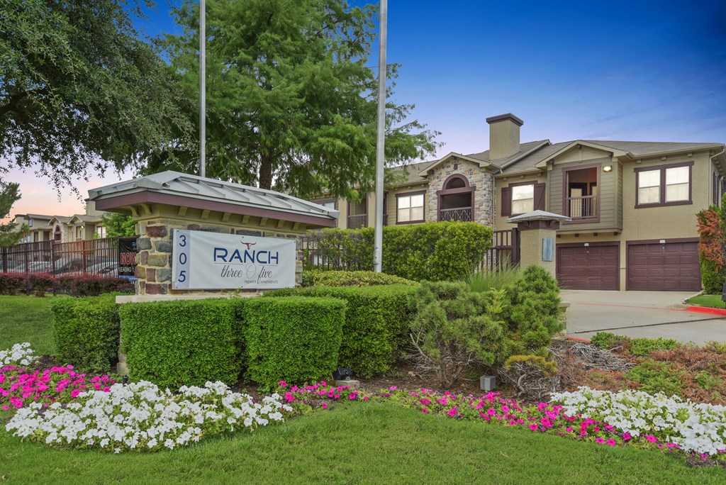 a home with a ranch sign in front of a yard with flowers