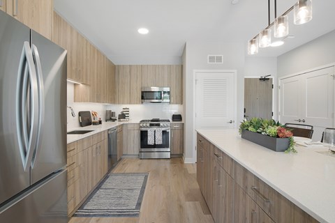 A modern kitchen with a stainless steel refrigerator and wooden cabinets.
