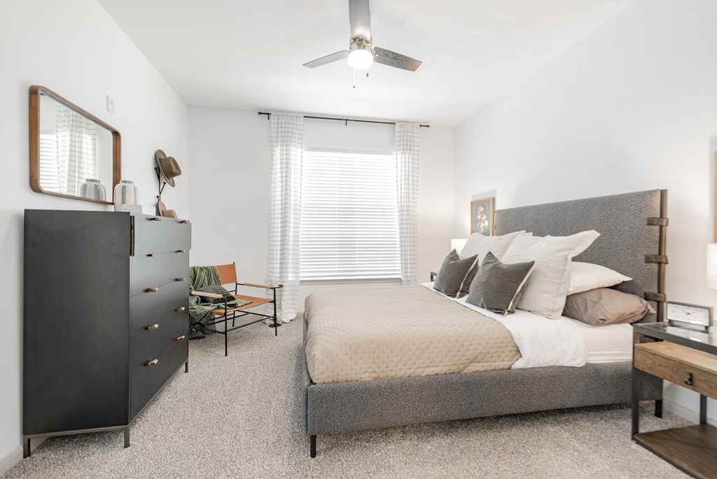 a bedroom with a bed and a dresser and a ceiling fan
