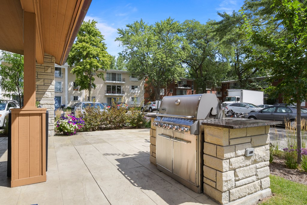 a gas grill on the side of a patio with trees