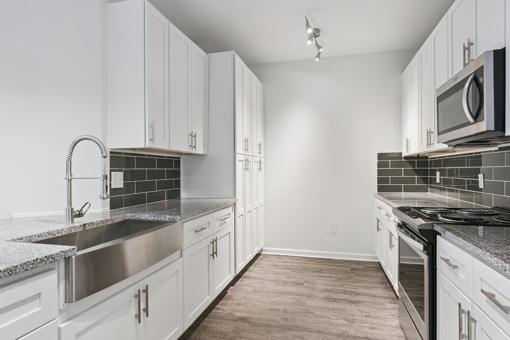 A kitchen with white cabinets and a black stove top.