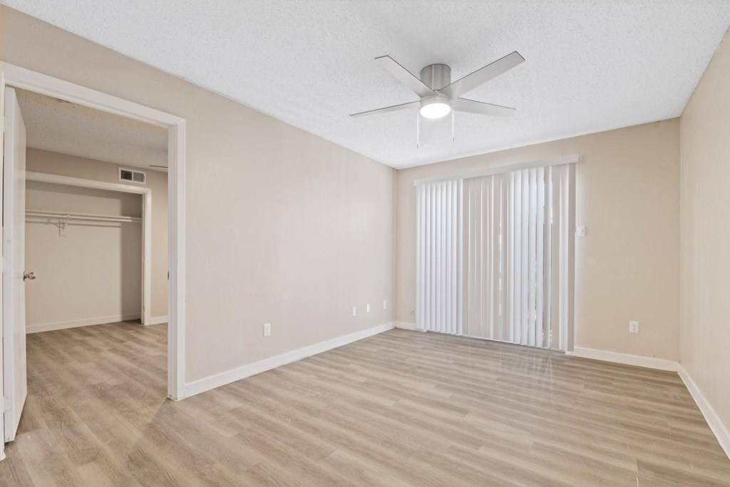the spacious living room with sliding glass doors and a ceiling fan