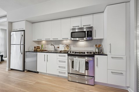 A modern kitchen with white cabinets and stainless steel appliances.