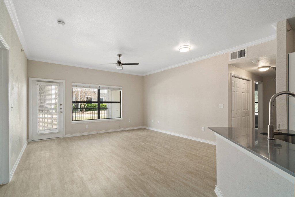 a living room with a large window and a kitchen