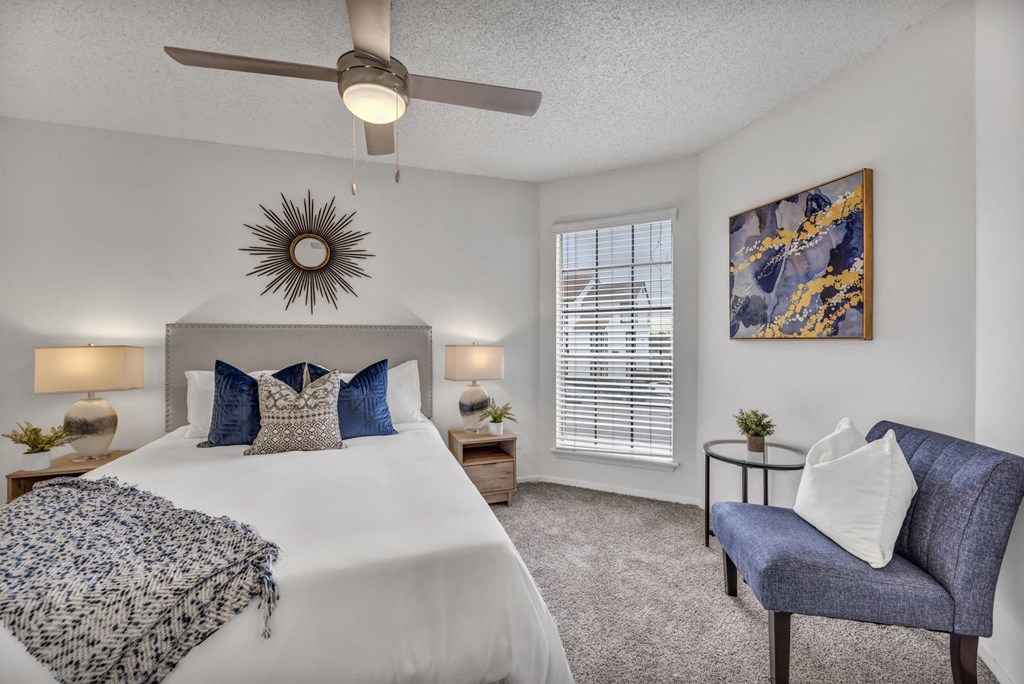 A bedroom with a bed, a chair, and a ceiling fan.