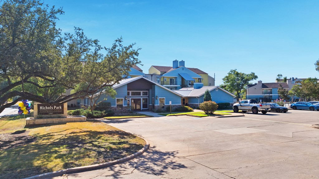 A parking lot with cars and a building with a sign that says Nicholas Park.