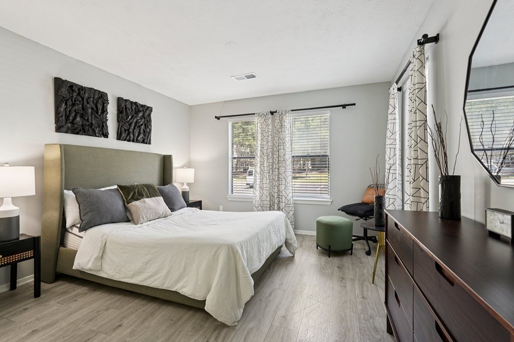 A bedroom with a large bed and a window with curtains.
