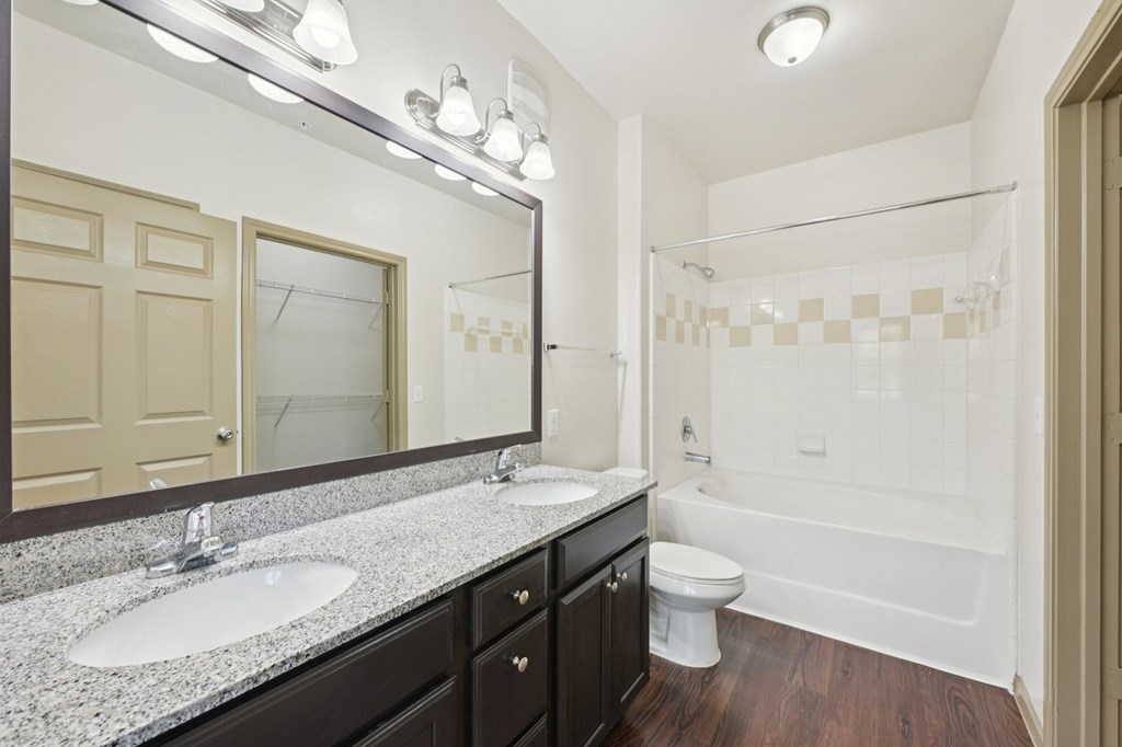 A bathroom with a sink, mirror, and bathtub.