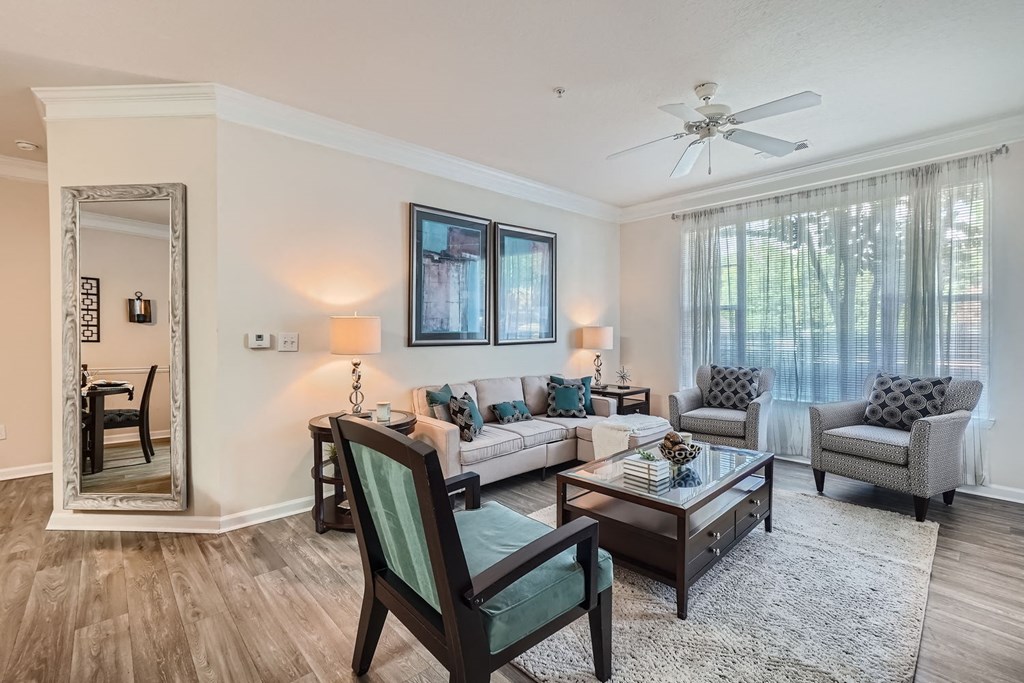 A living room with a chair, a sofa, a table, and a mirror.